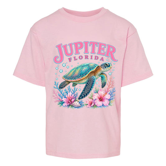 A light pink short-sleeve t-shirt featuring a colorful graphic of a sea turtle, coral, and flowers, with the text 'JUPITER FLORIDA' printed above it.