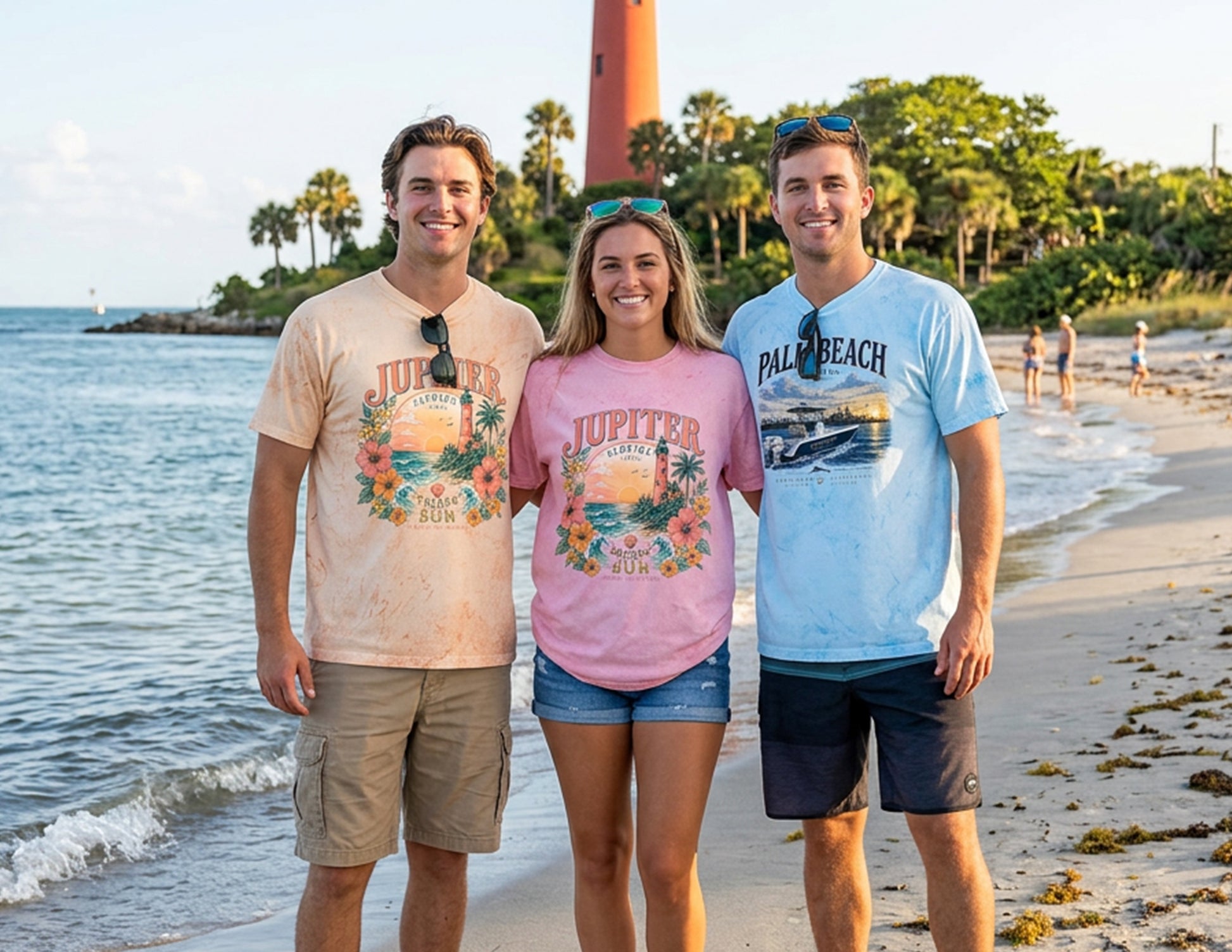 Lifestyle photo of men and women wearing Jupiter Florida and Palm Beach graphic T-shirts featuring coastal beach, boating, and lighthouse artwork at the iconic Jupiter Inlet Lighthouse in South Florida.