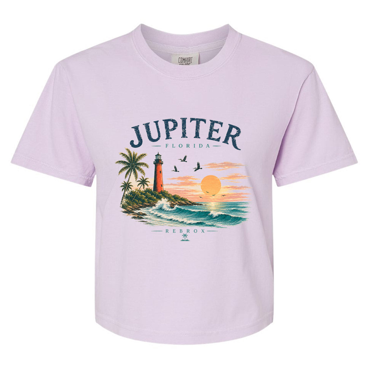 A light lavender short-sleeve crewneck t-shirt featuring a colorful graphic print of a tropical Florida sunset with a lighthouse, palm trees, and the text 'JUPITER - FLORIDA' and 'REBROX'.
