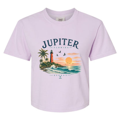 A light lavender short-sleeve crewneck t-shirt featuring a colorful graphic print of a tropical Florida sunset with a lighthouse, palm trees, and the text 'JUPITER - FLORIDA' and 'REBROX'.