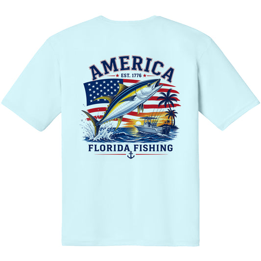 A light blue short-sleeve t-shirt with a large graphic print on the back. The graphic features a yellow tuna fish jumping in front of an American flag, with the text 'AMERICA EST.